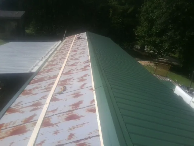 Old rusted panels beside newly installed green metal roofing — Wind Damage Roof Repair by Roofing Brothers in Ekron