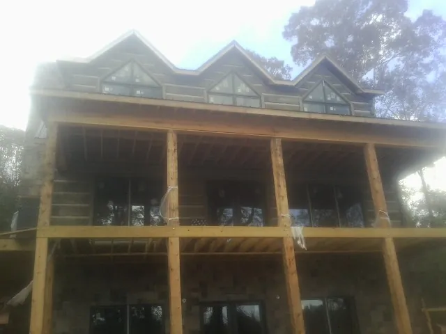 Dormers and porch framing on a large log home under construction — Roof Coating work by our crew in Ekron