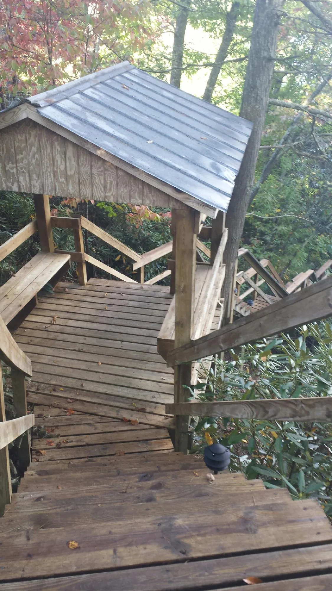 Metal roofed shelter over wooden steps on a wooded walkway — Skylight Repair & Installation work by our crew in Ekron