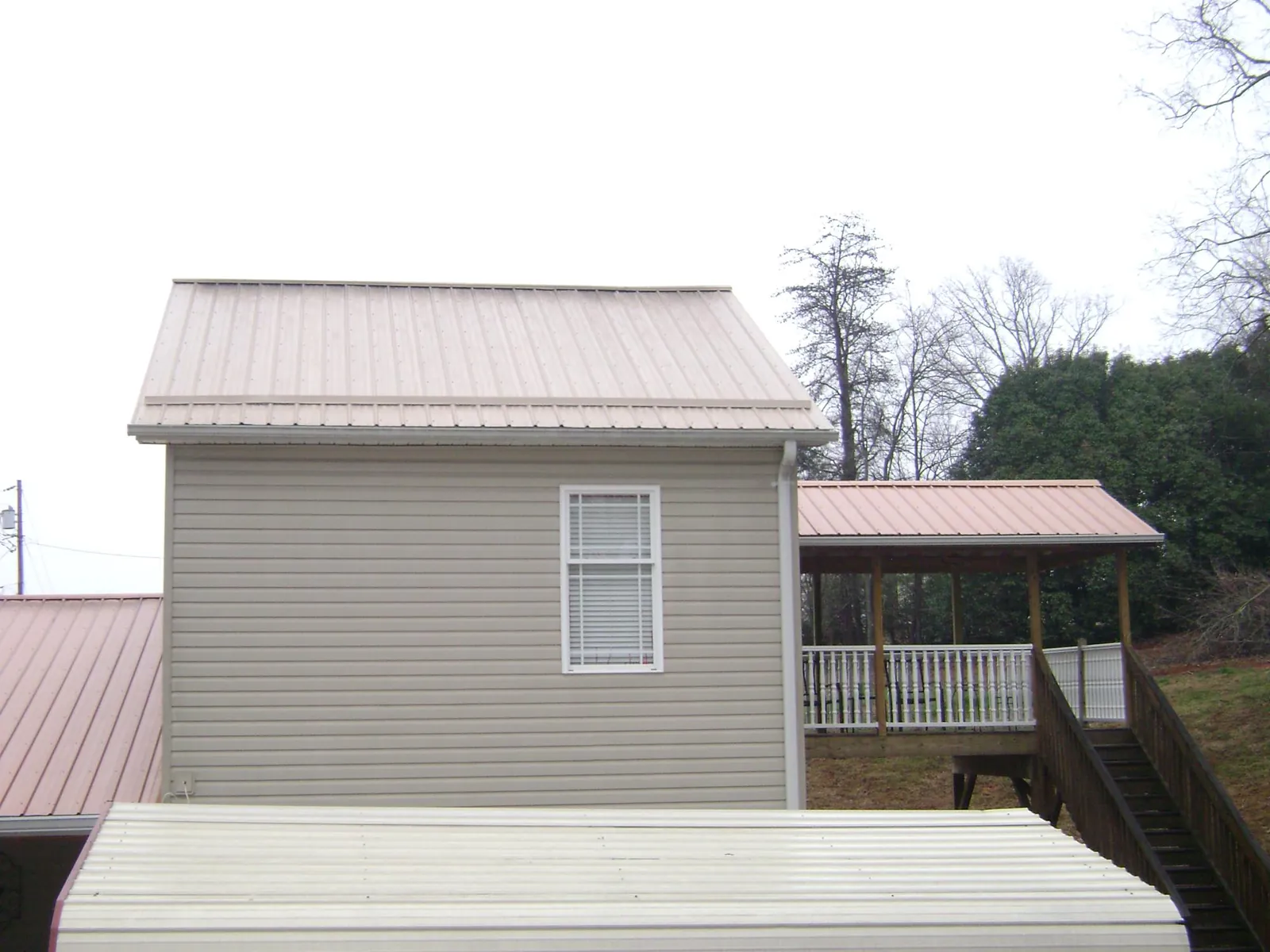 Tan metal roofs on a two story addition and attached porch, from a Roof Replacement job in Ekron